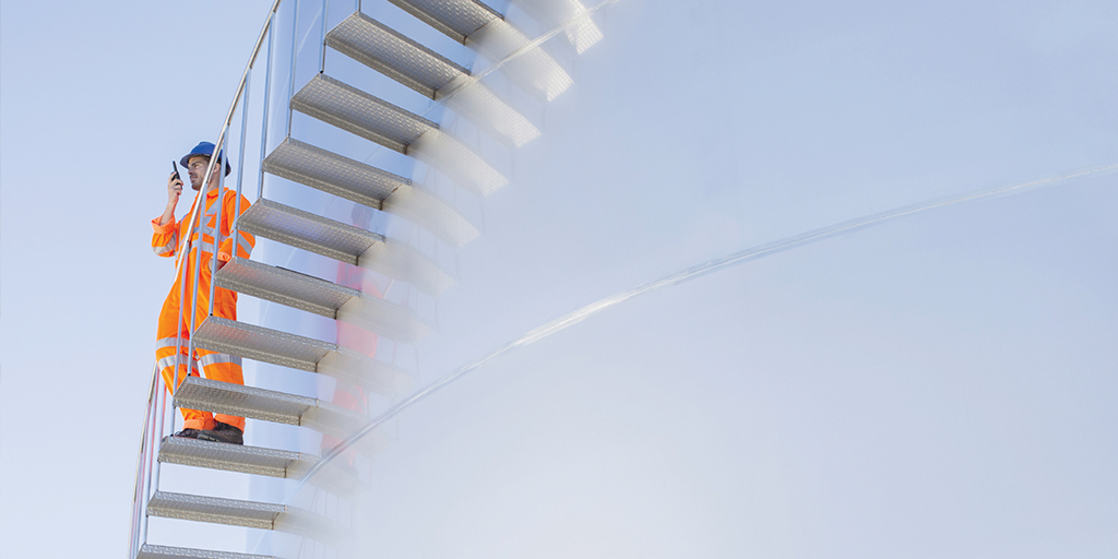 Operator climbing stairs on the side of storage tank